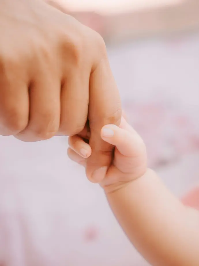 a close up of a person holding a baby's hand